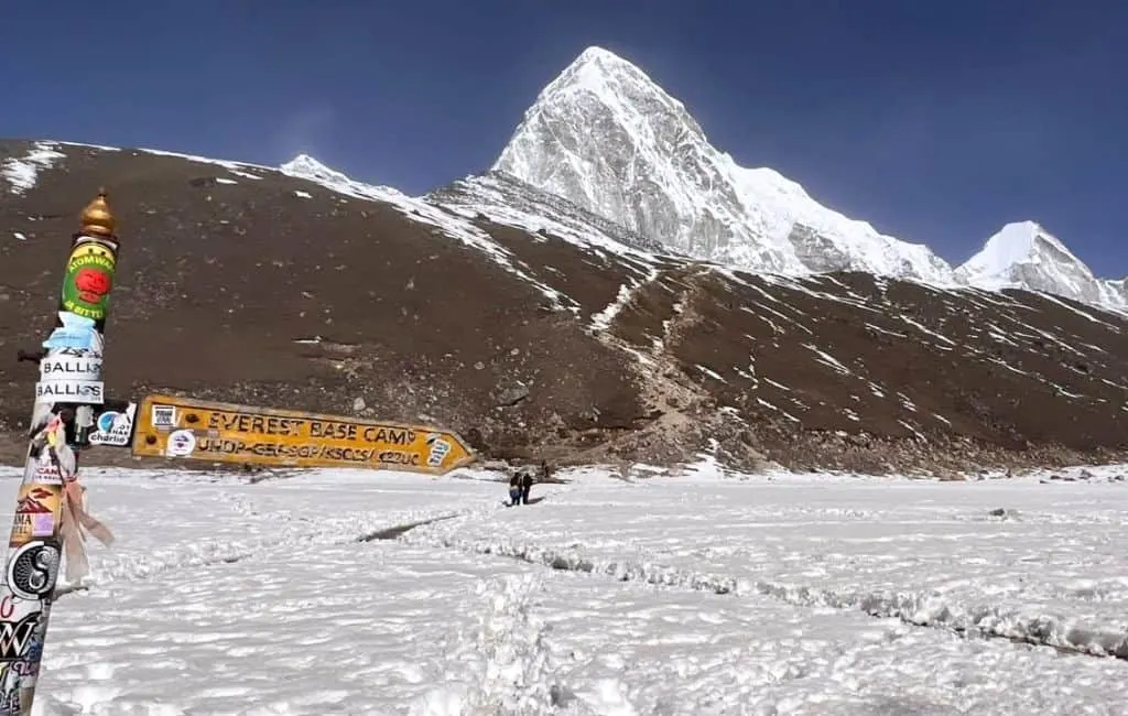 Arrow pointing the way to Everest Base Camp with Himalayan mountains in the background.