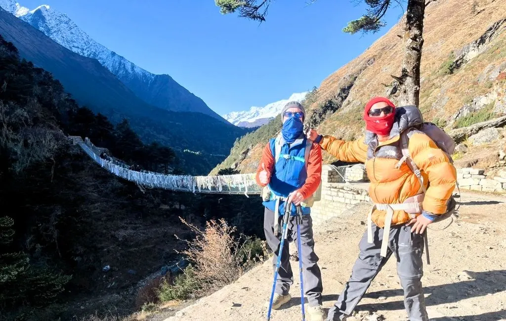 Everest Base Camp Trek – Trekkers posing near a suspension bridge with mountains in the background on the trail from Pheriche to Namche